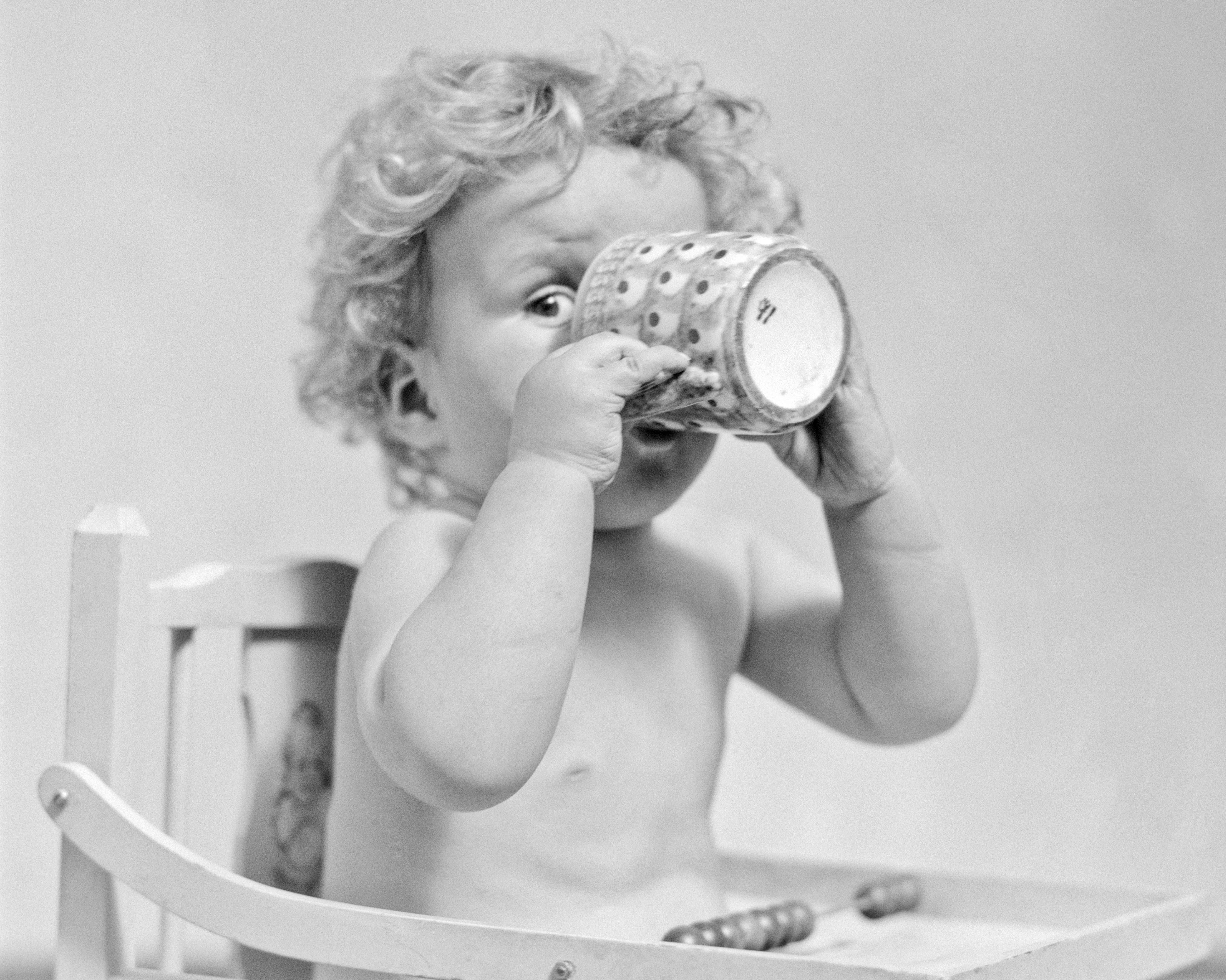 A baby boy sips from a mug