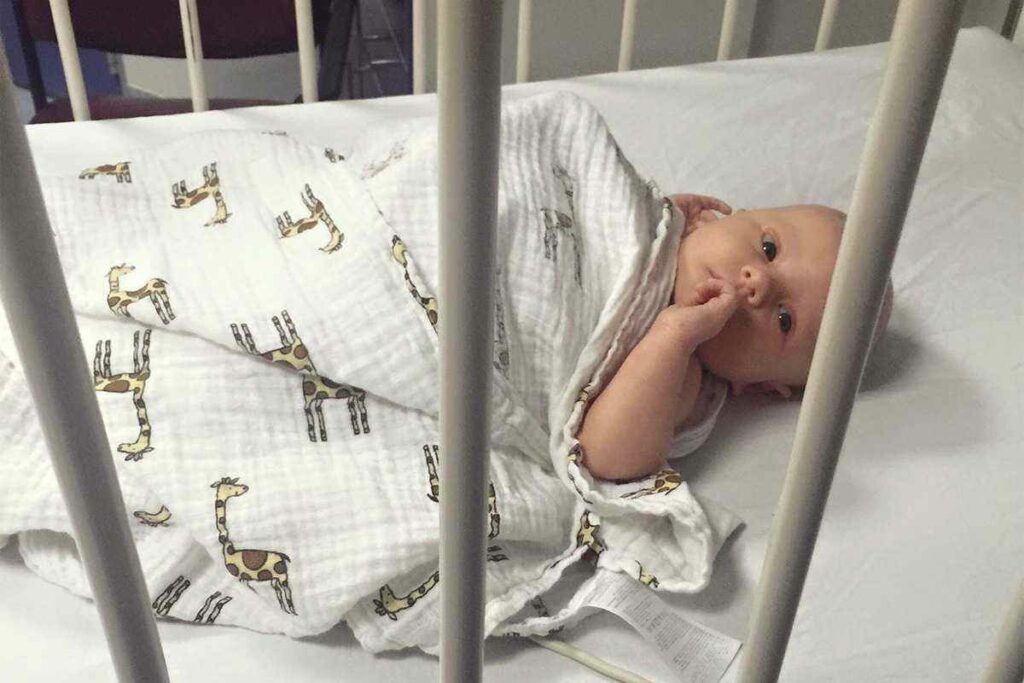 Baby, Riley Hughes, looks towards the camera from his hospital bed.