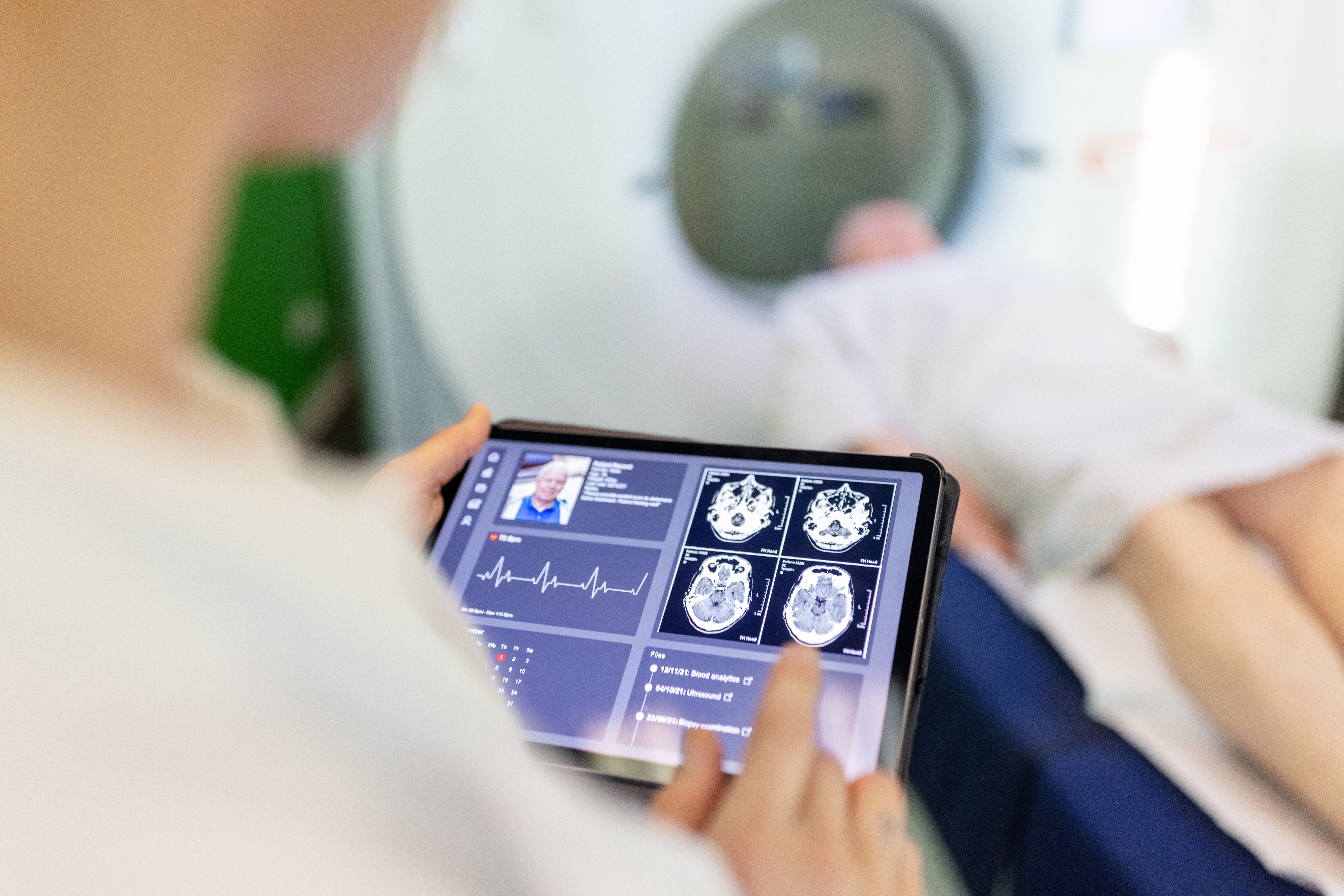 Neurologist examining patient's CAT scan images on digital table in clinic